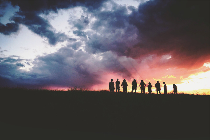 people standing under stormy skies